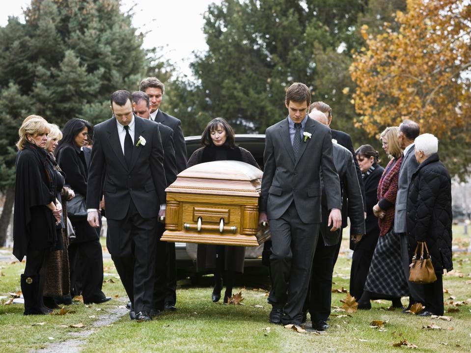 A family lowering a casket into the ground