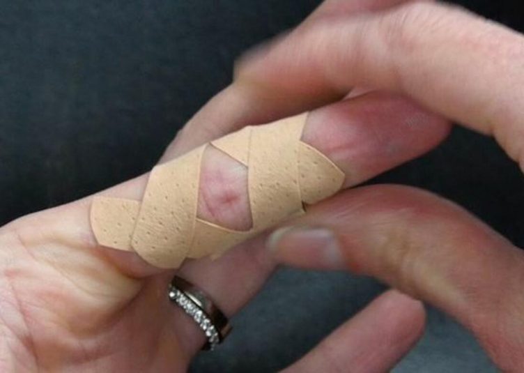 Bandaged finger with a paper cut.