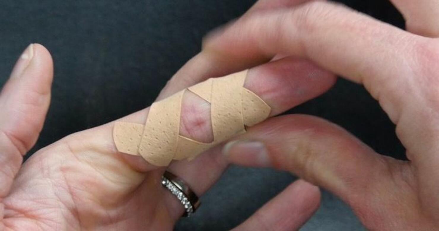 Bandaged finger with a paper cut.