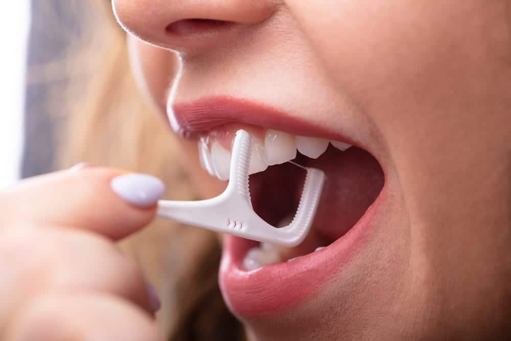 A woman flossing her teeth.