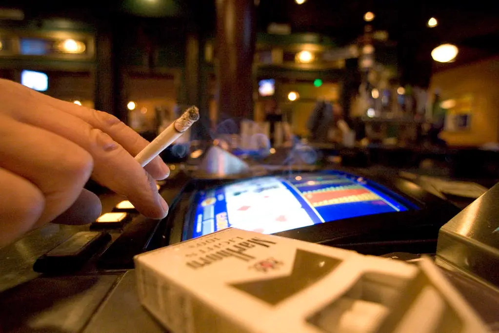 A man gambling with a pack of cigarettes.