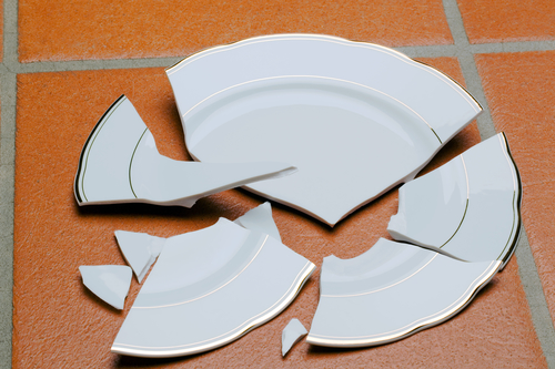 Picture of a broken plate on a dining hall floor.