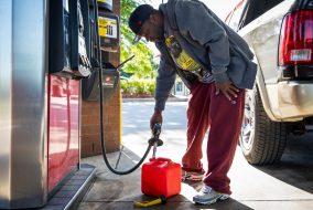 Picture of a man who looks mad and is pumping gas into a gas can.