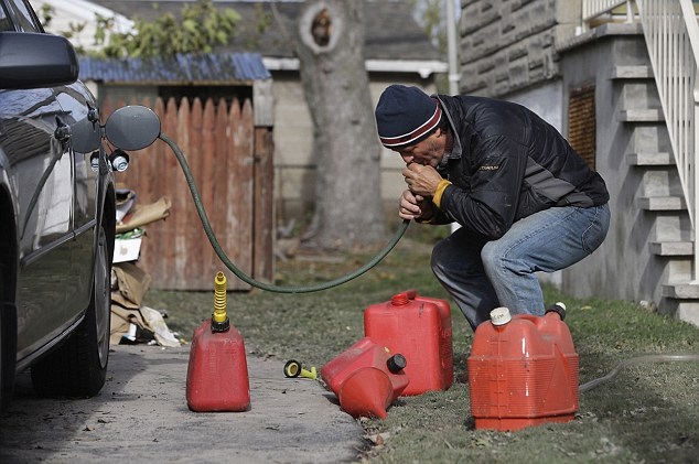 A man siphoning gas from a car.