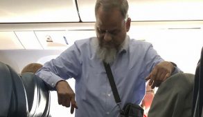 Man at the back of an airplane standing up