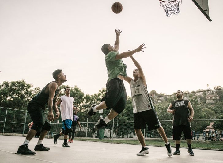 Men playing basketball in a park.
