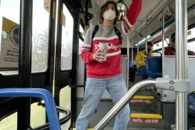 Man standing, holding handle inside of bus