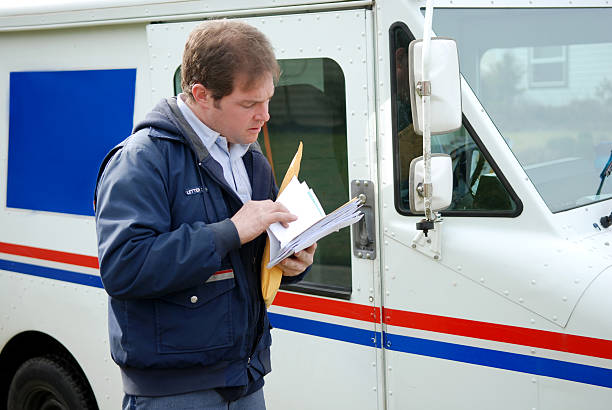 A mailman is sorting through the mail and looking for stamps.