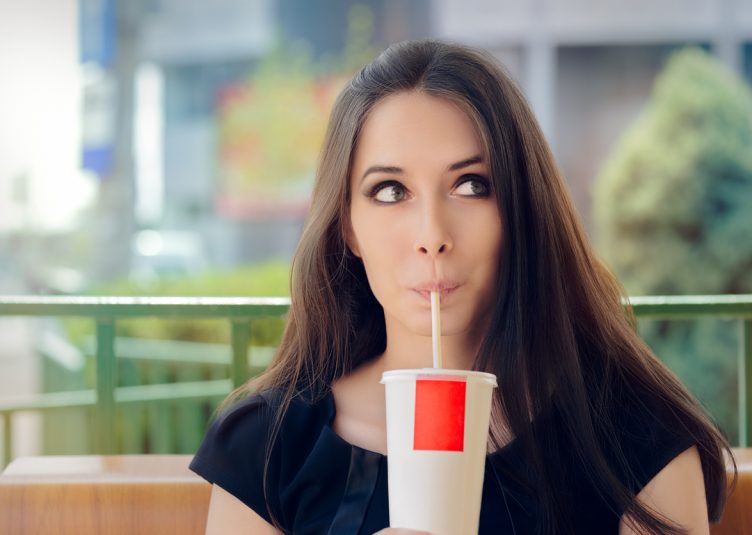 Portrait of a funny girl drinking trough a straw