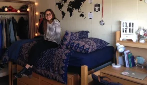 freshman girl sitting on half-lofted bed