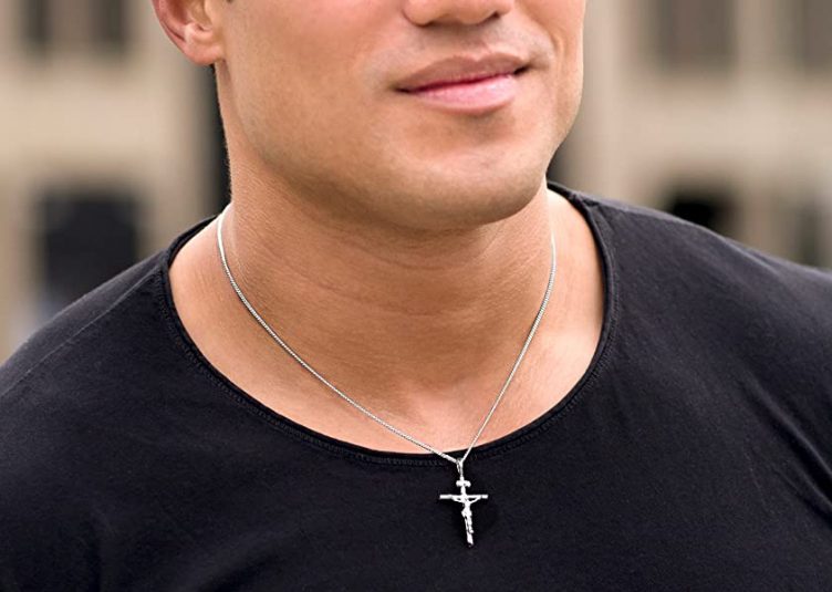 Close-up of a cross necklace worn by a man in a black t-shirt.