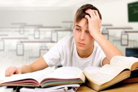 A boy with his head in his hands frustrated with studying.