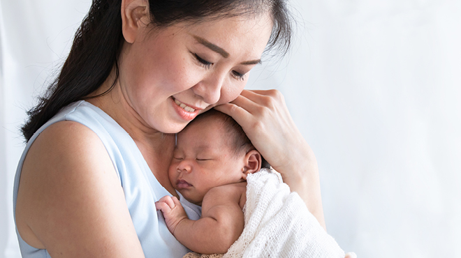 A woman hold a newborn baby to her chest.