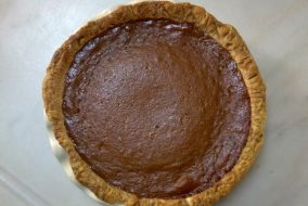A pumpkin pie sits on a tiled surface.