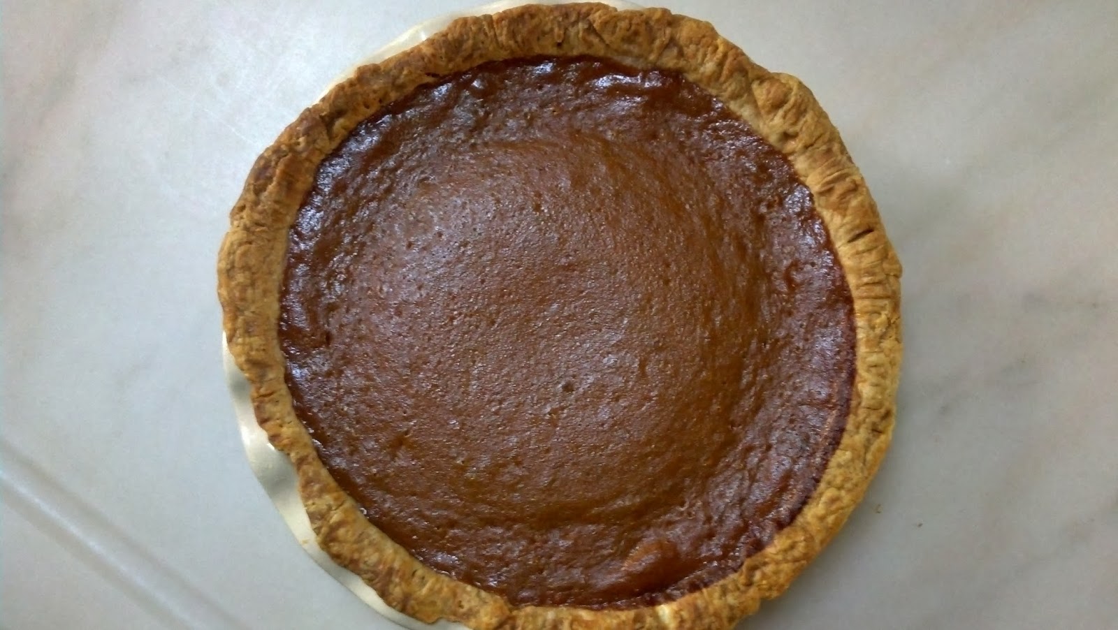 A pumpkin pie sits on a tiled surface.