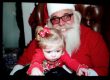A child sits on the lap of a tense-looking Santa Claus