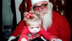 A child sits on the lap of a tense-looking Santa Claus