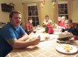 A man sits at a dining room table eating with kids of varying ages.
