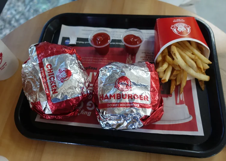 A carton of fries, two cups of ketchup, and two Wendy's burgers sit on a tray.