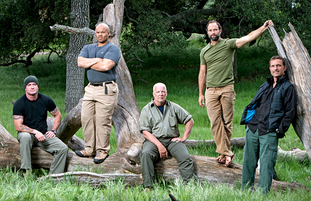A group of five men pose on a fallen tree.