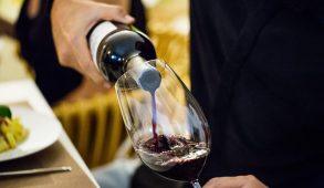 A man pouring red wine into a glass.